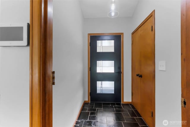 doorway featuring stone tile floors and baseboards