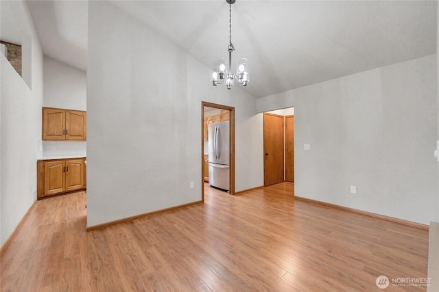 interior space with an inviting chandelier, baseboards, light wood finished floors, and high vaulted ceiling