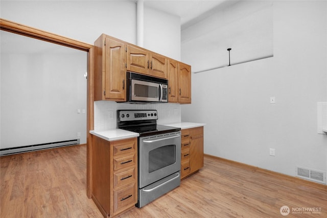 kitchen with visible vents, light wood-style flooring, stainless steel appliances, light countertops, and tasteful backsplash