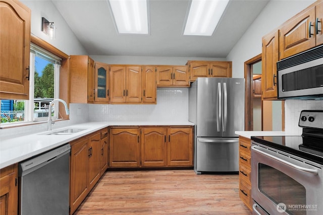 kitchen with a sink, lofted ceiling, appliances with stainless steel finishes, and light countertops