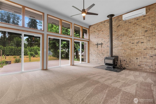 unfurnished living room with a towering ceiling, a wood stove, a wall unit AC, and carpet floors