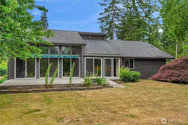 rear view of house featuring a lawn and roof with shingles