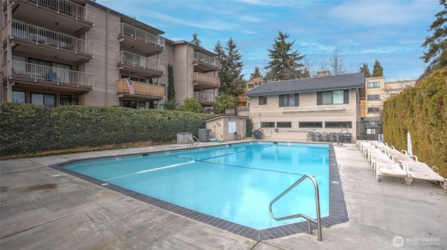 community pool featuring a patio area, central AC, and fence