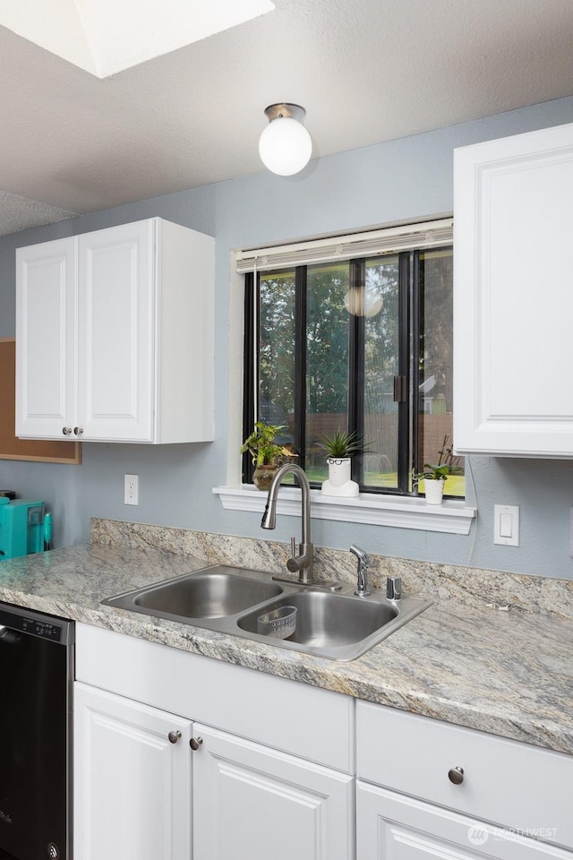 kitchen with black dishwasher, sink, and white cabinets