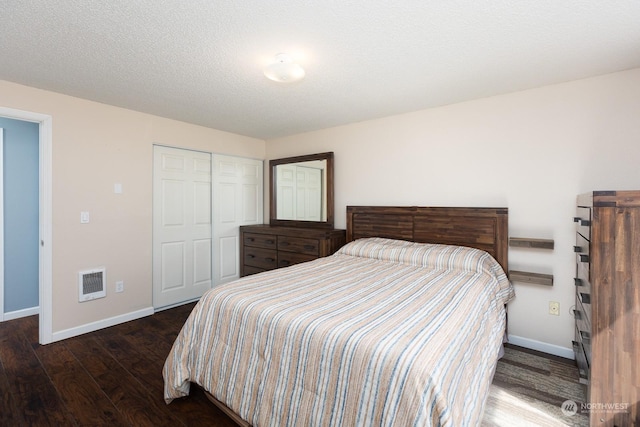 bedroom featuring dark wood-type flooring, a textured ceiling, and a closet