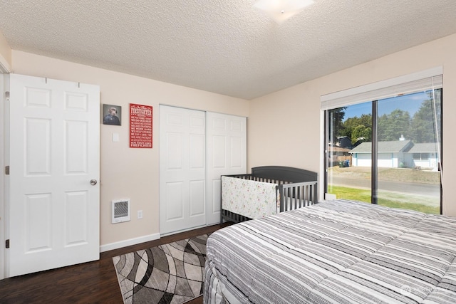 bedroom featuring a closet, dark hardwood / wood-style floors, access to exterior, and a textured ceiling