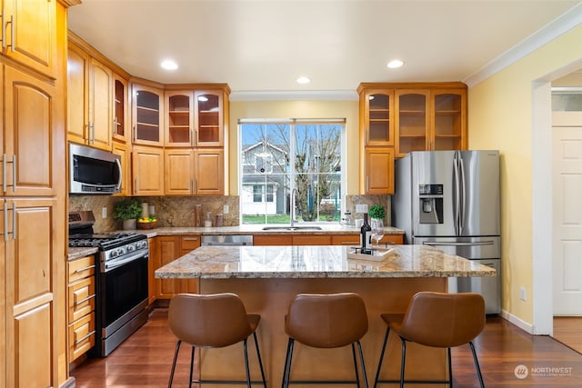 kitchen featuring sink, a kitchen island with sink, stainless steel appliances, light stone countertops, and decorative backsplash