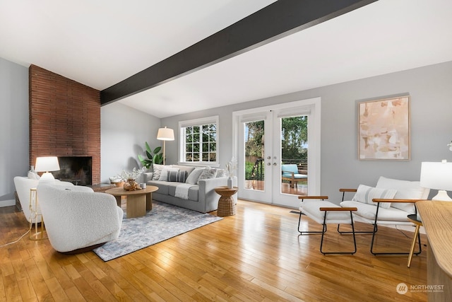 living room with french doors, beamed ceiling, a fireplace, and light wood-type flooring