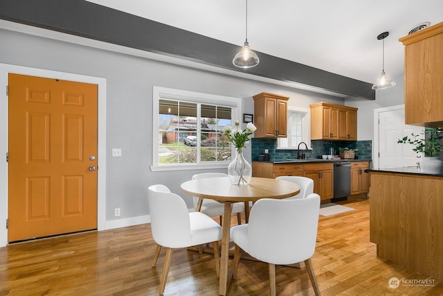 dining room featuring sink, beamed ceiling, and light wood-type flooring