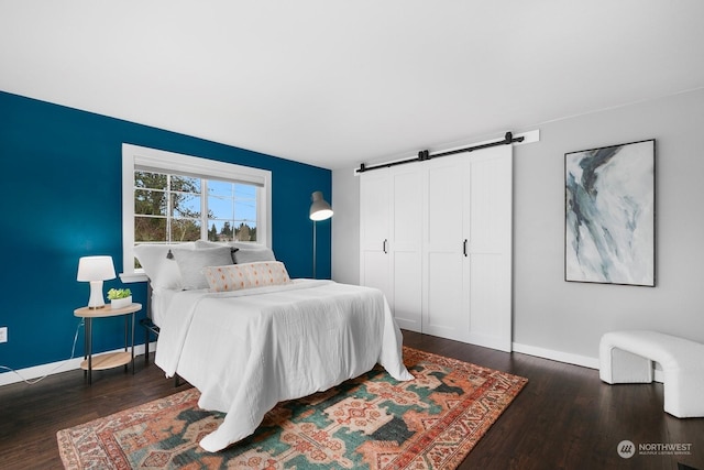 bedroom with dark hardwood / wood-style floors, a barn door, and a closet