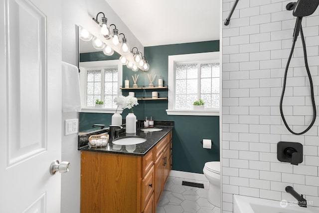 full bathroom with tile patterned flooring, vanity, tiled shower / bath, and toilet