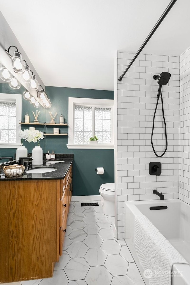 full bathroom featuring vanity, tiled shower / bath, and toilet