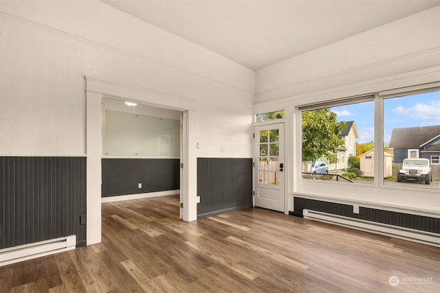 empty room featuring baseboard heating and hardwood / wood-style floors