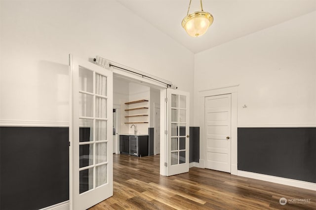 empty room featuring dark hardwood / wood-style floors, sink, high vaulted ceiling, and french doors