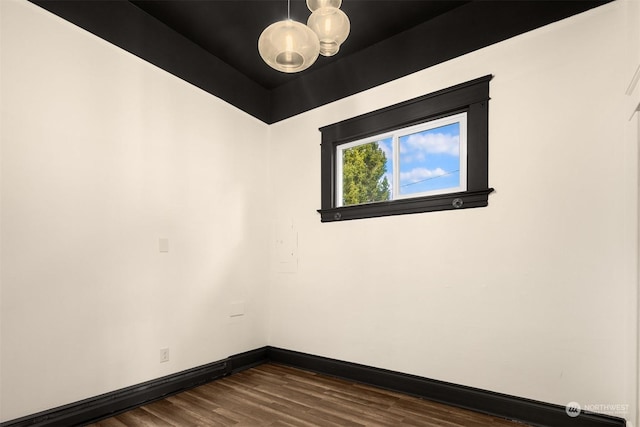 empty room featuring a notable chandelier and dark hardwood / wood-style flooring