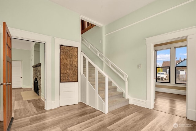 stairway with hardwood / wood-style floors and a fireplace