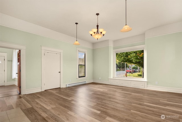 spare room featuring wood-type flooring, a notable chandelier, and baseboard heating