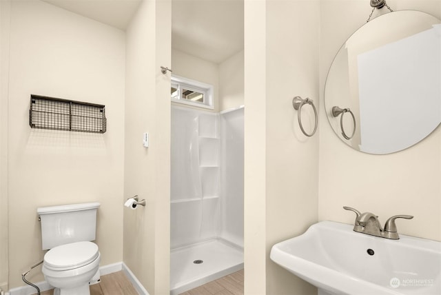 bathroom with wood-type flooring, a shower, sink, and toilet