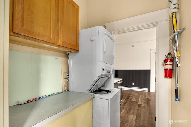 laundry room featuring cabinets, a baseboard heating unit, stacked washer / drying machine, and dark hardwood / wood-style floors