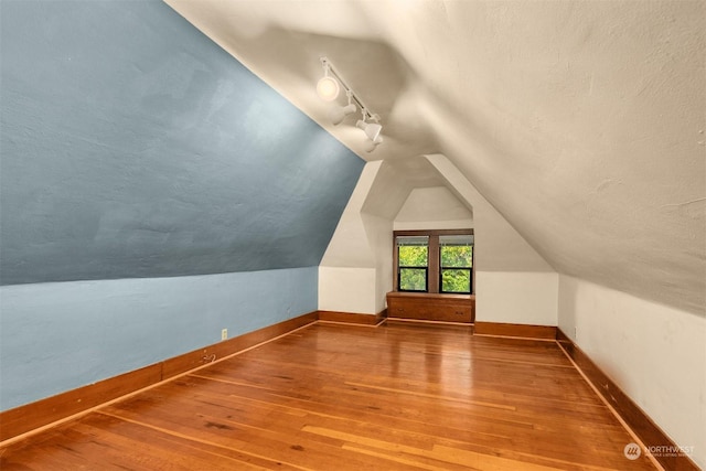 bonus room with lofted ceiling, wood-type flooring, and a textured ceiling