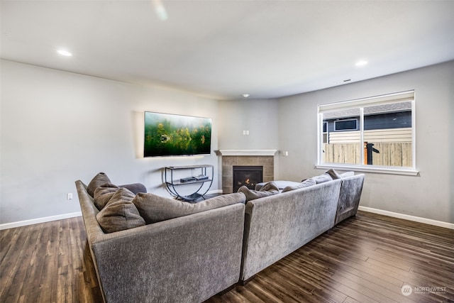 living room with a tiled fireplace and dark hardwood / wood-style flooring