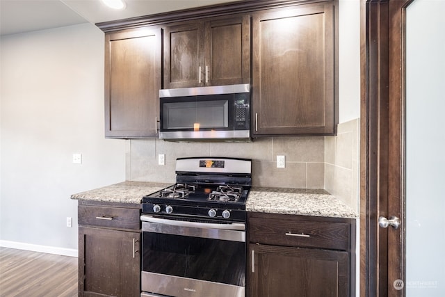 kitchen featuring appliances with stainless steel finishes, dark brown cabinets, and backsplash