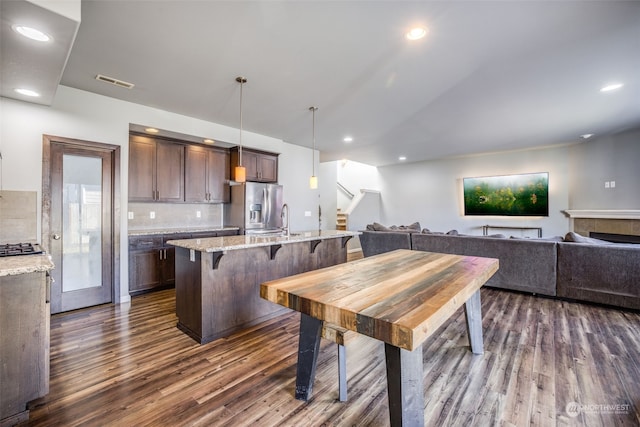 kitchen featuring hanging light fixtures, light stone countertops, a kitchen breakfast bar, and stainless steel fridge with ice dispenser