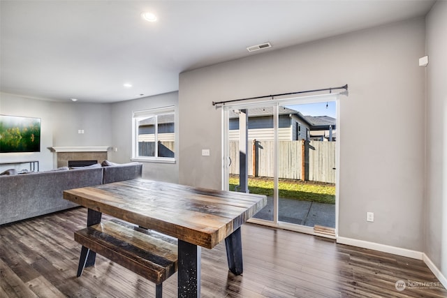 dining space with a healthy amount of sunlight, dark hardwood / wood-style floors, and a tile fireplace