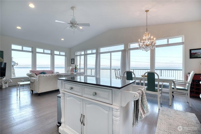 kitchen with pendant lighting, lofted ceiling, dark hardwood / wood-style floors, white cabinets, and ceiling fan with notable chandelier