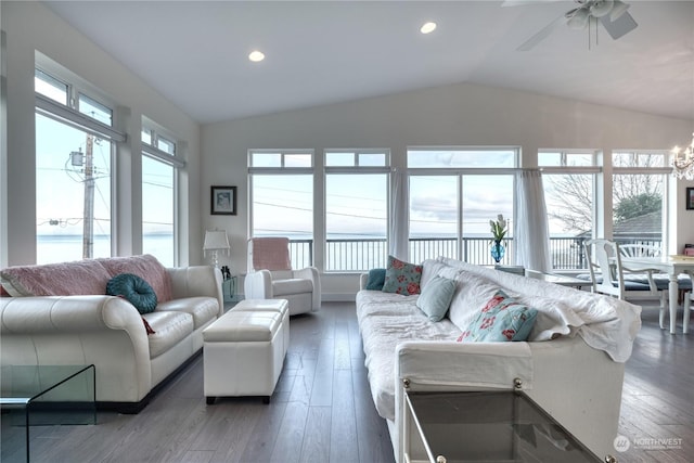 living room with lofted ceiling, ceiling fan with notable chandelier, dark wood-type flooring, and a healthy amount of sunlight