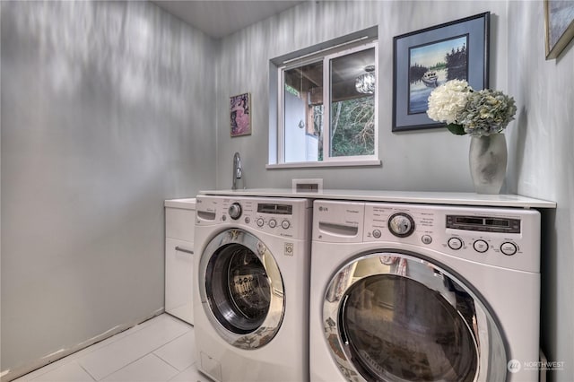 washroom featuring cabinets, light tile patterned flooring, and washing machine and clothes dryer