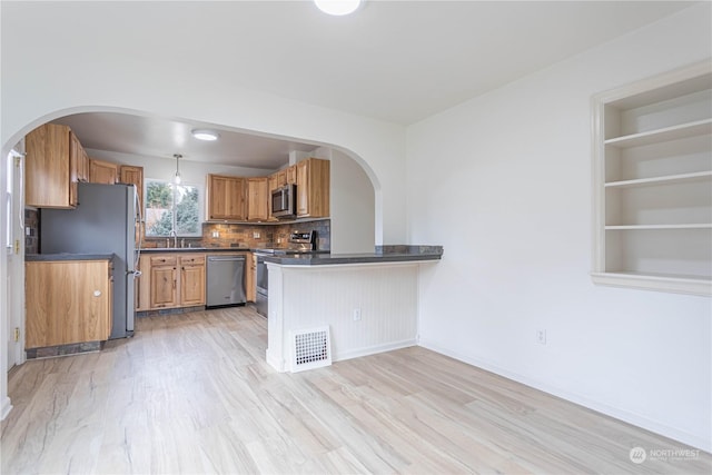 kitchen with tasteful backsplash, light hardwood / wood-style floors, kitchen peninsula, stainless steel appliances, and built in shelves