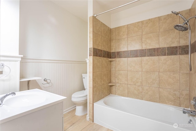 full bathroom with sink, tiled shower / bath combo, wood-type flooring, and toilet