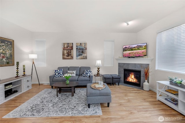 living area with light wood-type flooring, a fireplace, and baseboards