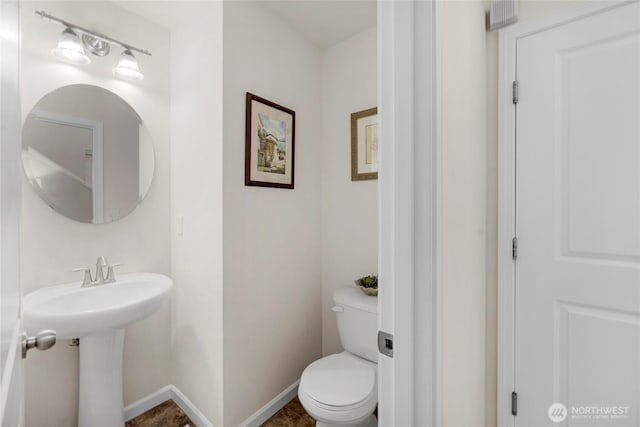 half bathroom with toilet and baseboards