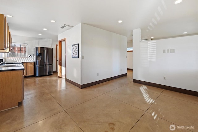 interior space featuring tasteful backsplash, stainless steel fridge with ice dispenser, and concrete flooring