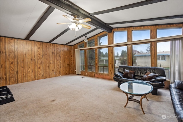 carpeted living room with ceiling fan, vaulted ceiling with beams, and wooden walls