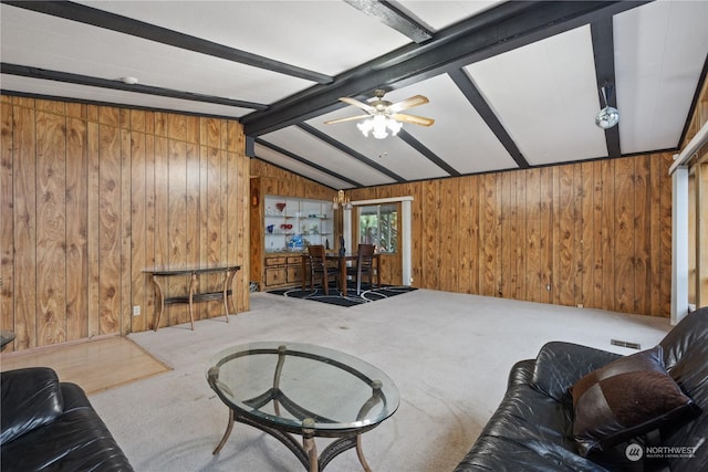 carpeted living room with ceiling fan, wooden walls, and lofted ceiling with beams