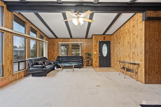 carpeted living room featuring ceiling fan, lofted ceiling with beams, and wood walls