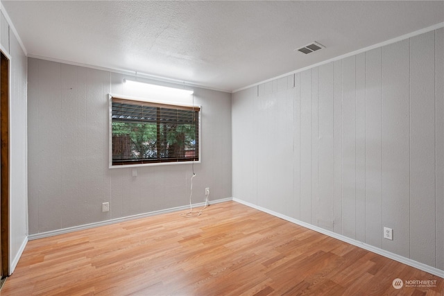 empty room with crown molding, wood-type flooring, and a textured ceiling