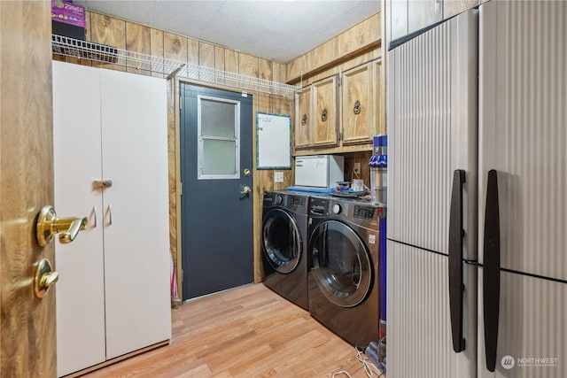 washroom with washer and clothes dryer, light hardwood / wood-style floors, and cabinets