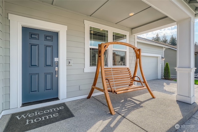 view of exterior entry with a garage and a porch