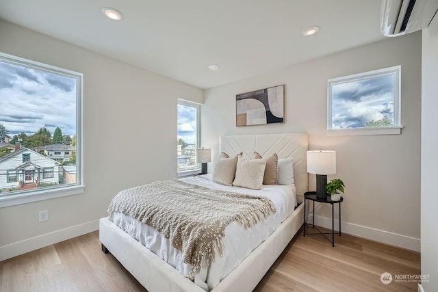 bedroom with wood-type flooring and a wall mounted AC