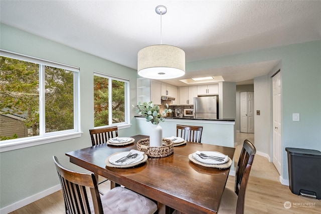 dining area with a skylight and light hardwood / wood-style flooring