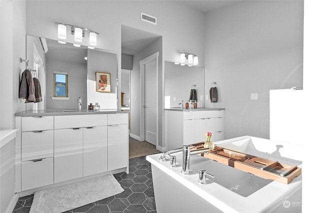 bathroom with a tub to relax in, vanity, and tile patterned floors