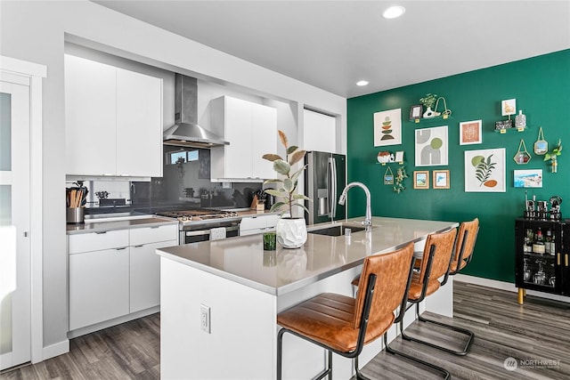 kitchen featuring sink, white cabinetry, stainless steel appliances, a center island with sink, and wall chimney exhaust hood