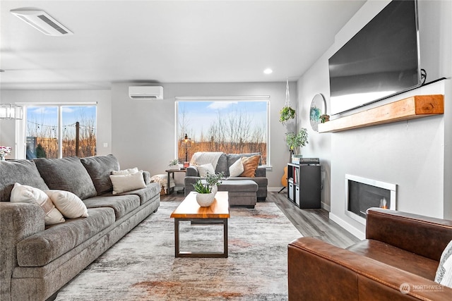 living room featuring a wall unit AC and light hardwood / wood-style floors