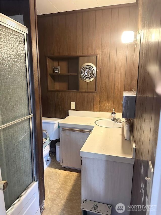 full bath with toilet, tile patterned floors, vanity, and wooden walls