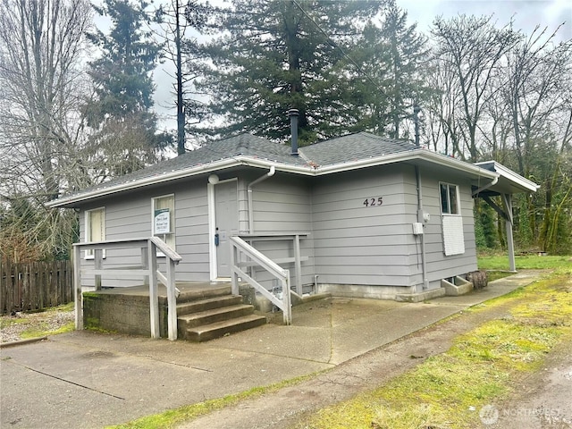 view of front facade featuring fence and roof with shingles