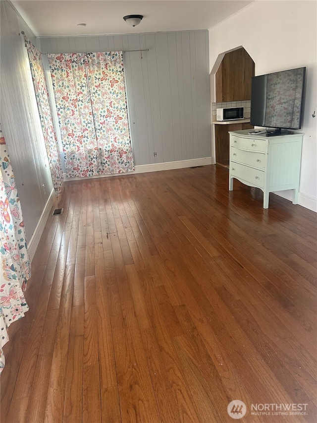 unfurnished living room featuring dark wood-style floors, visible vents, and baseboards